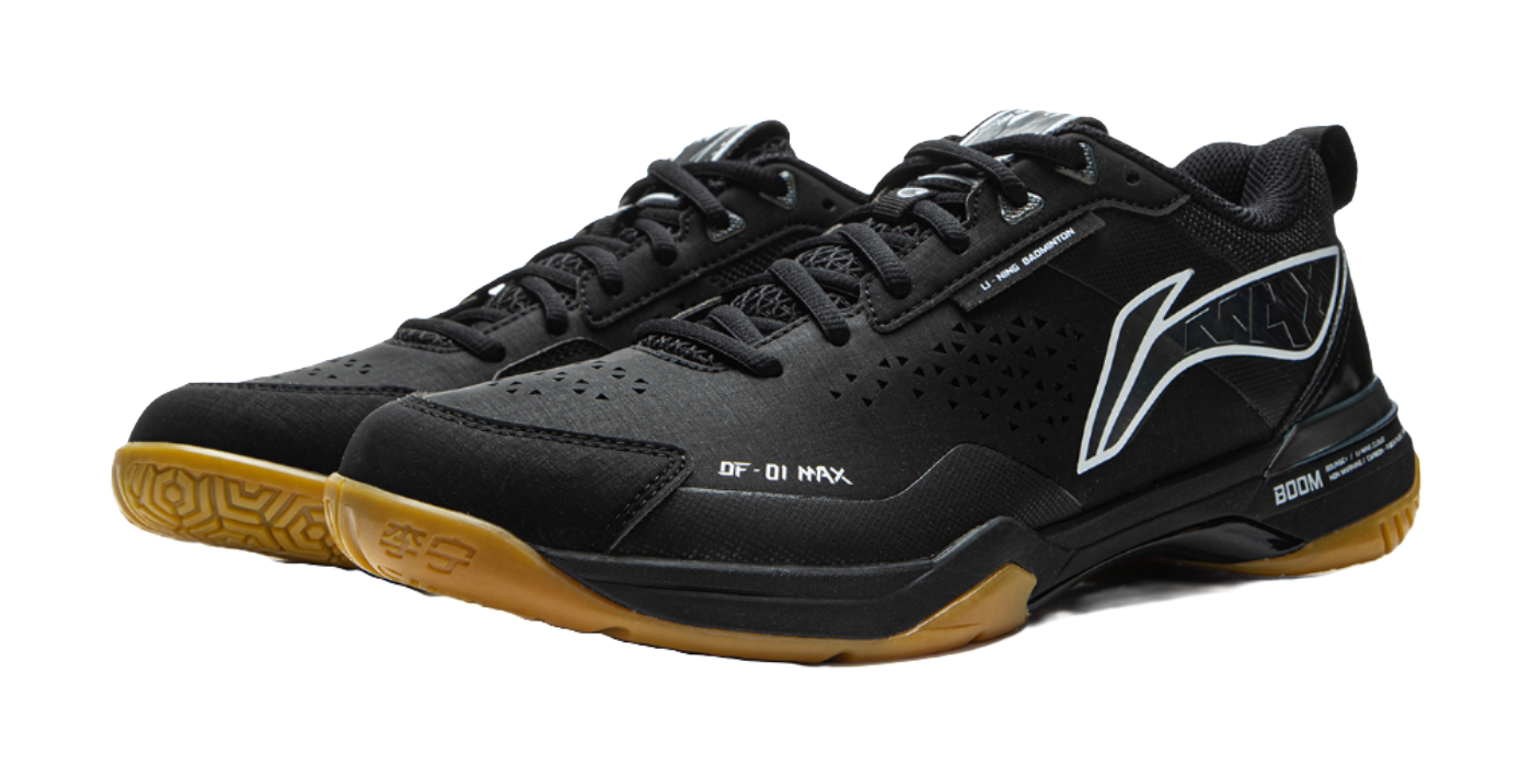 Black badminton shoe with gold outsole edge, black-and-white stripe, and BOOM sole panel.