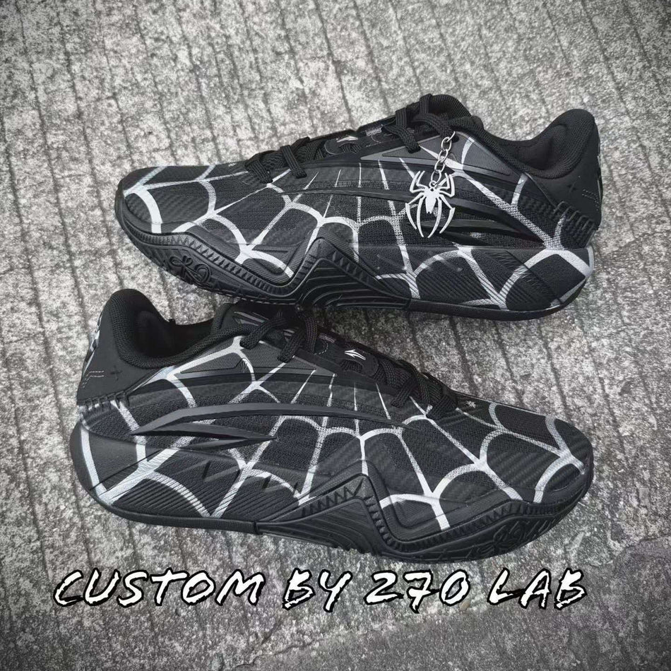 Pair of black basketball shoes with white spiderweb pattern and Spider emblem.