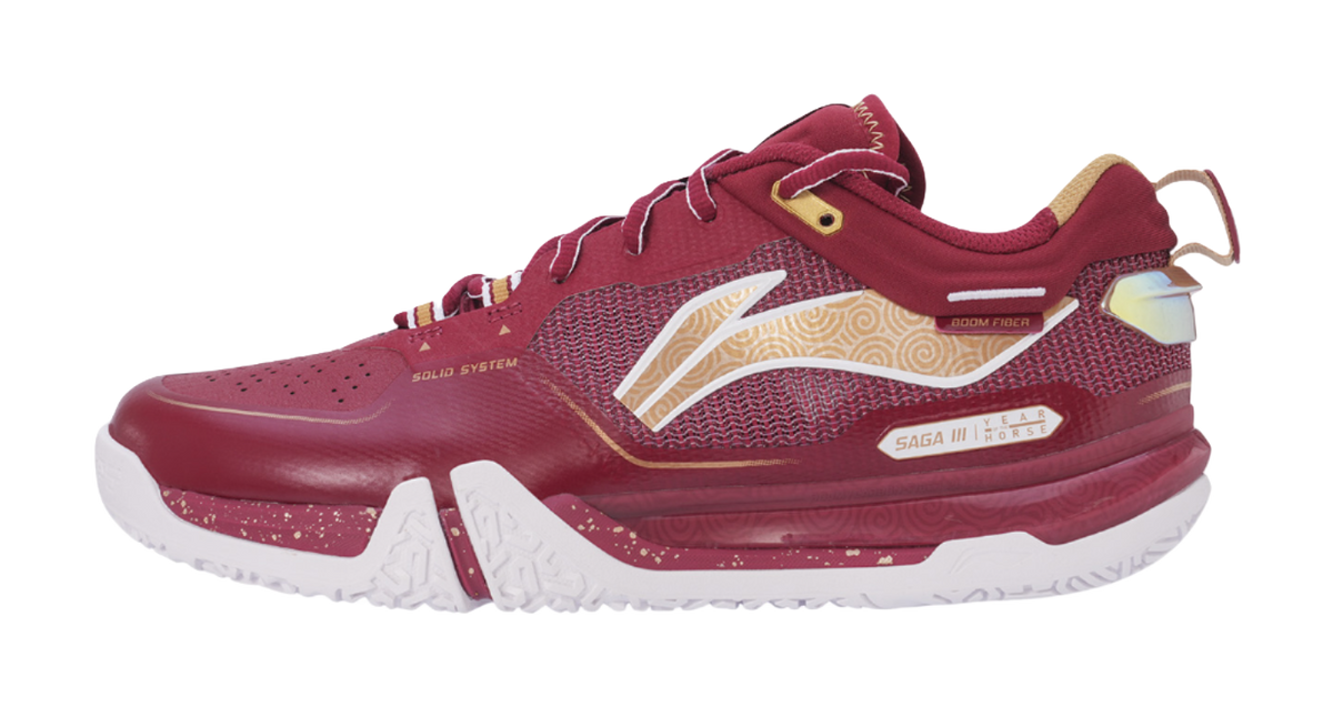 Red badminton shoe with mesh upper, gold accents, white outsole, and lace-up front.