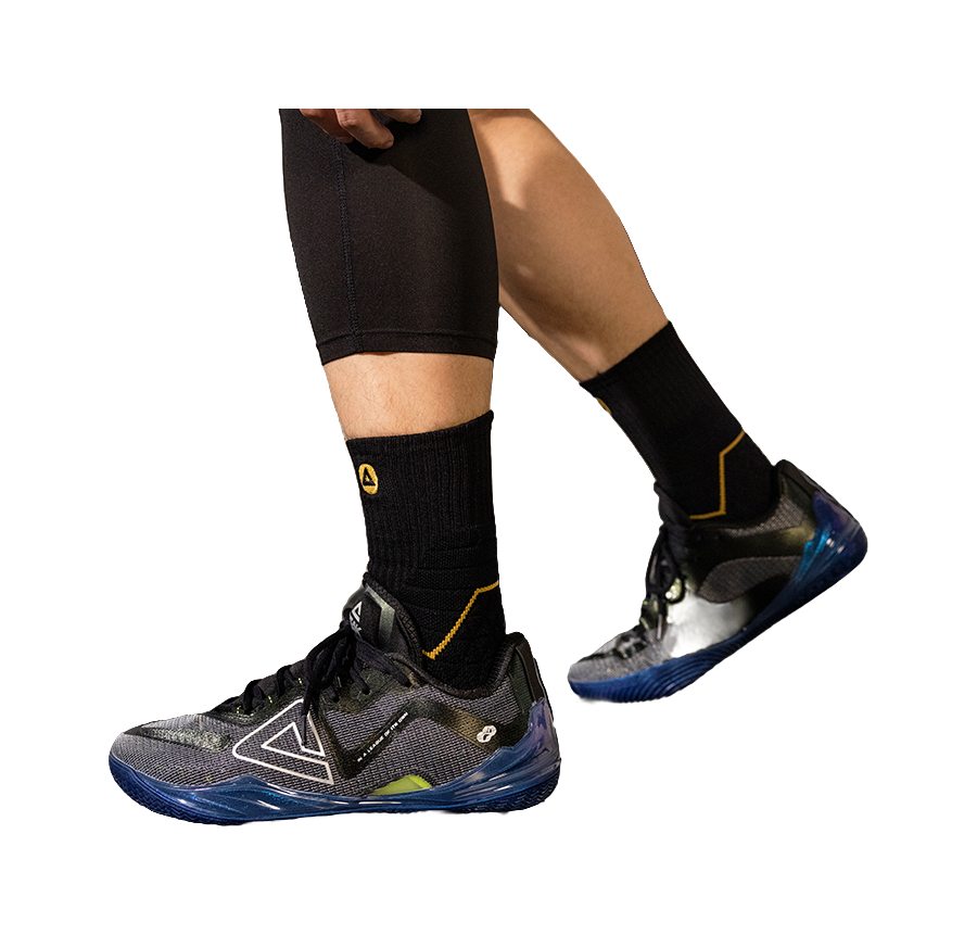 Basketball shoe on foot with black socks and blue-accent sole, black lace-up upper