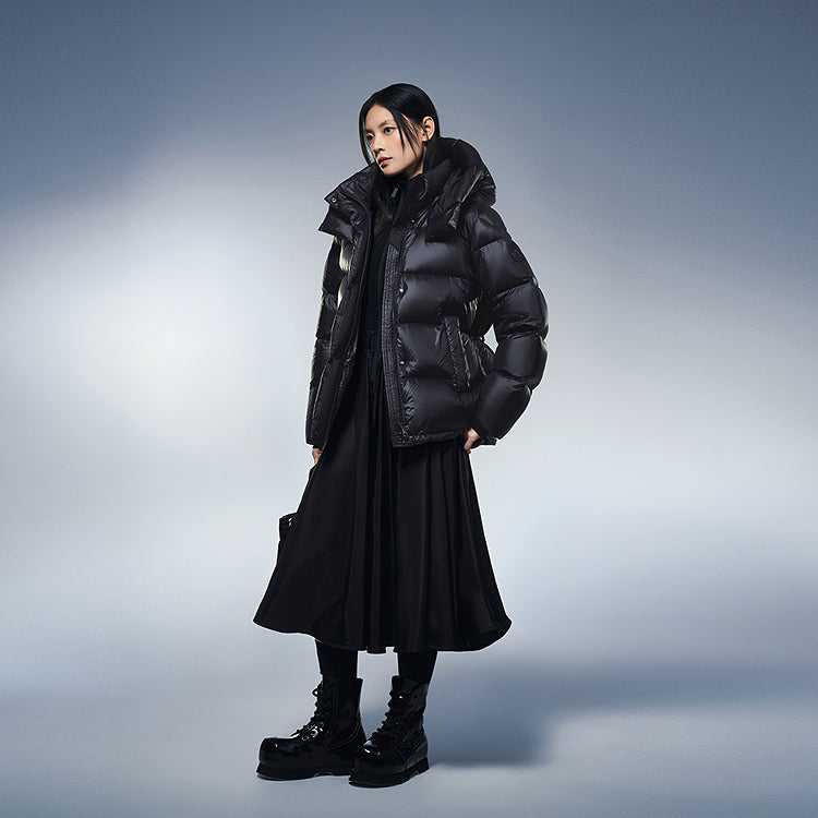 Black hooded puffer winter down jacket worn over a long skirt and boots