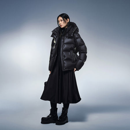 Black hooded puffer winter down jacket worn over a long skirt and boots