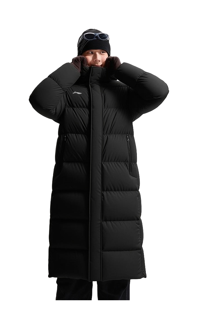 Black hooded long puffer down jacket on model with zip front and raised hood for warmth.