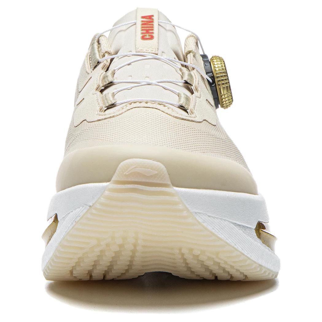 Women’s running shoes front view in light beige with lace-up vamp and gold heel dial.