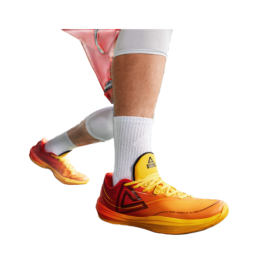 Basketball shoe on foot with orange/yellow lace-up upper and yellow collar patch