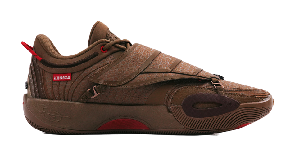 Brown basketball shoe side view with patterned strap, red lace accents, and tread sole