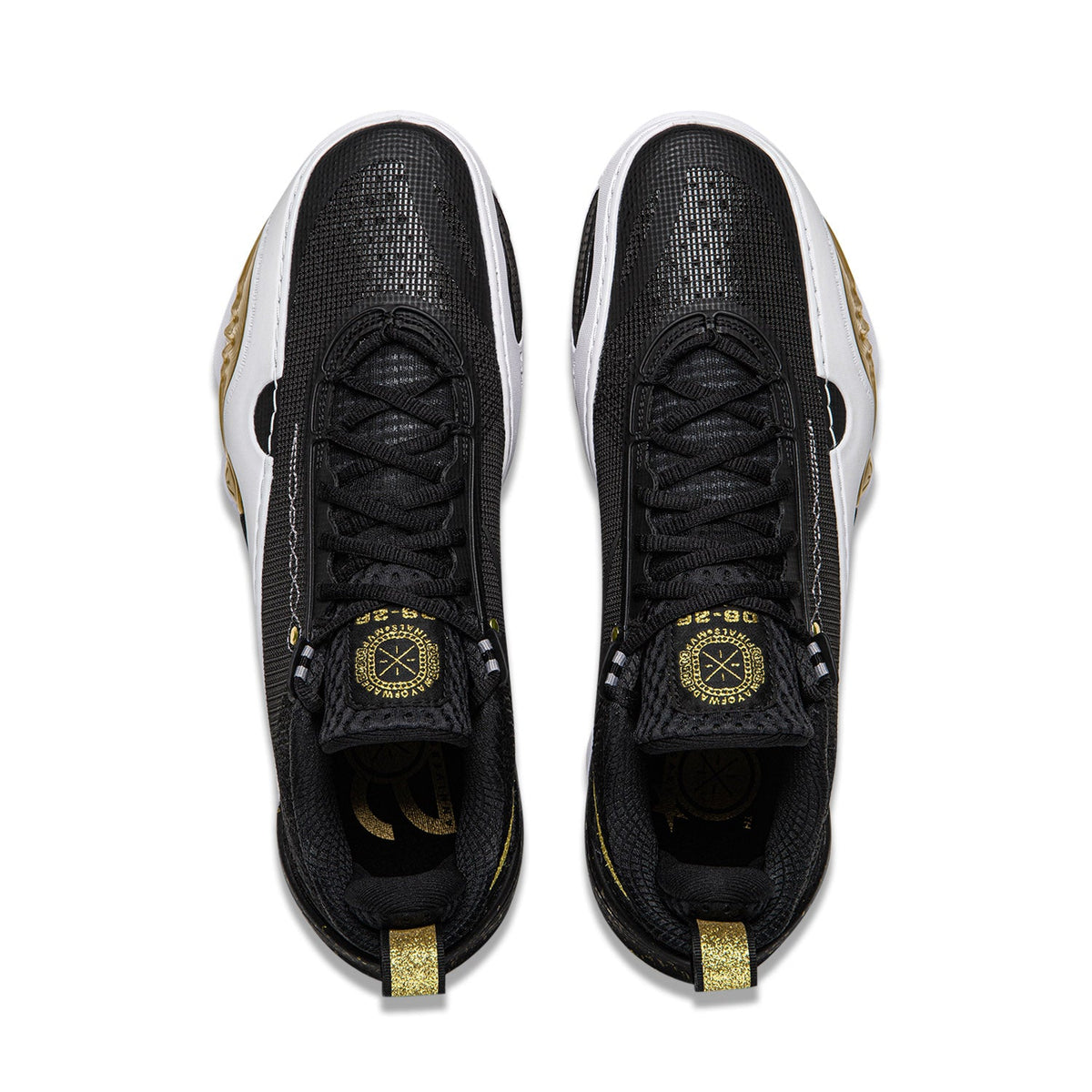 Pair of black sneakers with black laces, gold emblem, and white side trim