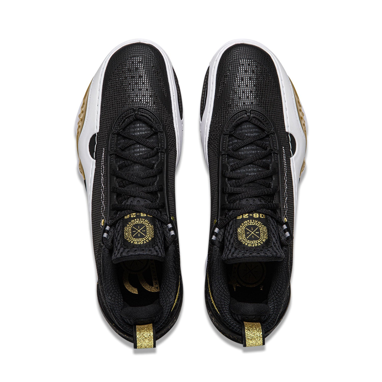 Pair of black sneakers with black laces, gold emblem, and white side trim