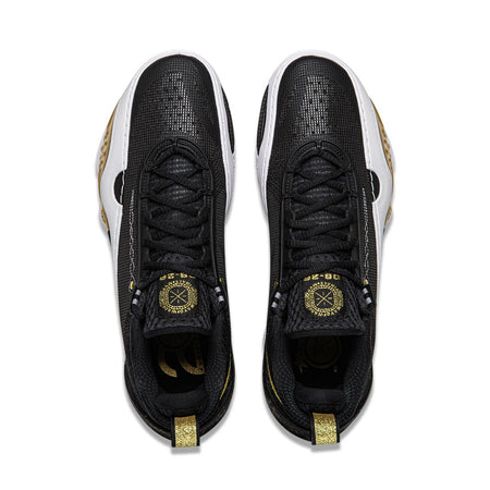 Pair of black sneakers with black laces, gold emblem, and white side trim