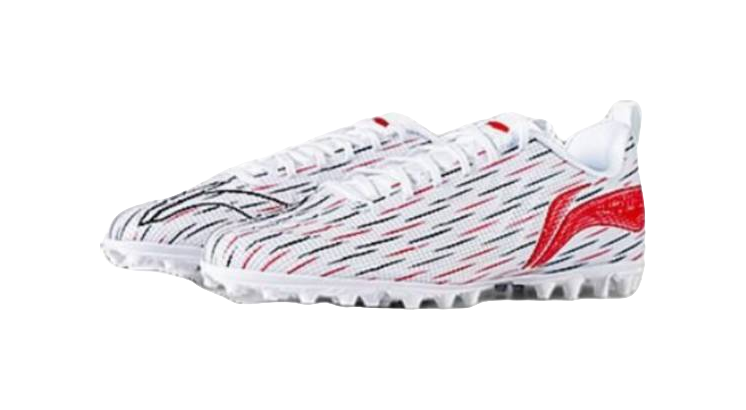 Youth soccer shoe side profile: white upper with red accents and black pattern lines