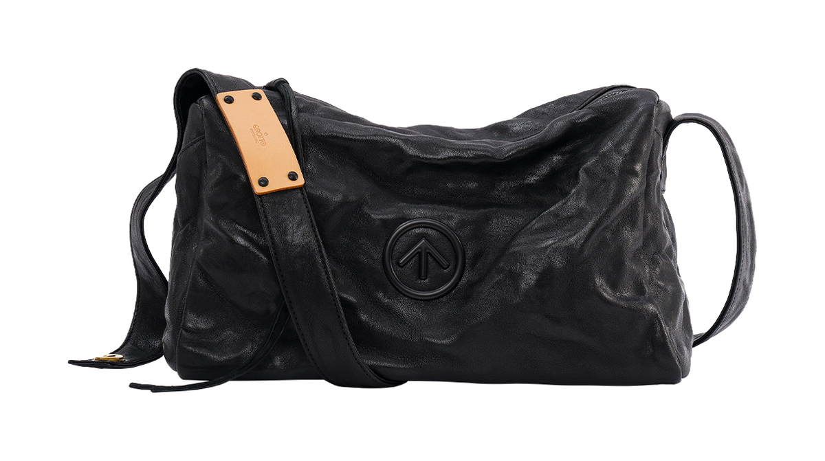 GROTTO black pleated sheepskin crossbody bag with tan label and embossed dark logo