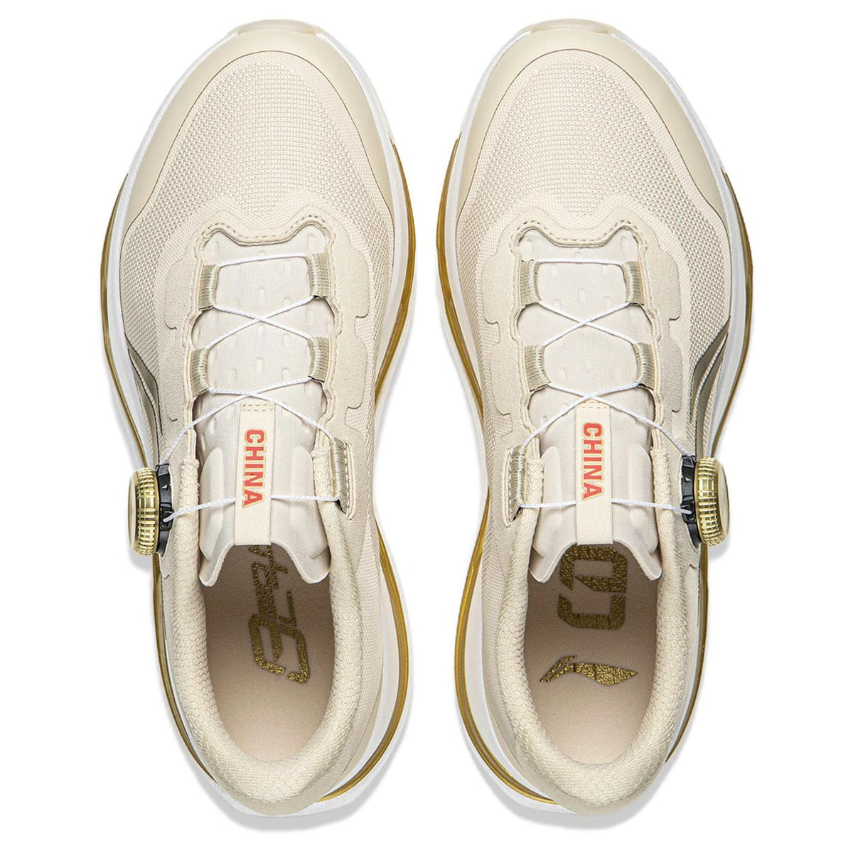 Pair of light beige running shoes shown from above with lace panels and gold accents.