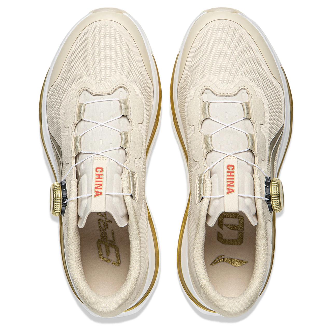 Pair of light beige running shoes shown from above with lace panels and gold accents.