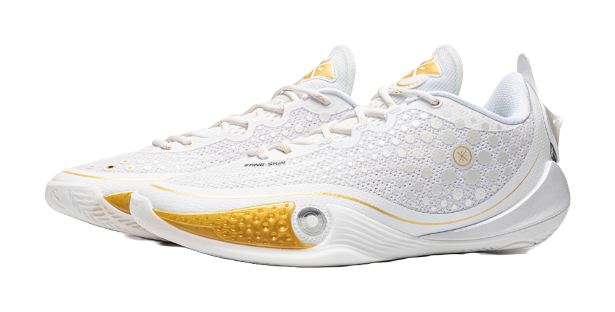 Low basketball shoe front profile, speckled white knit with gold logo accent and padded collar