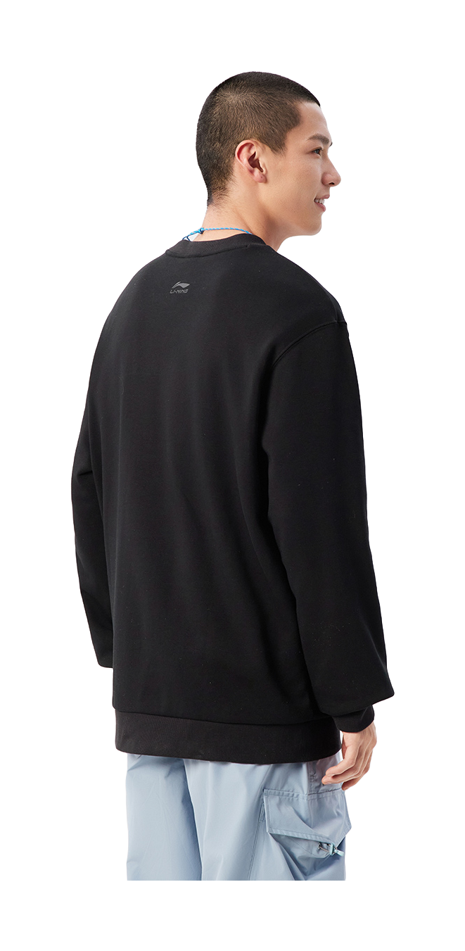 Black crewneck sweatshirt worn by model, back view; long sleeves, ribbed cuffs and hem.