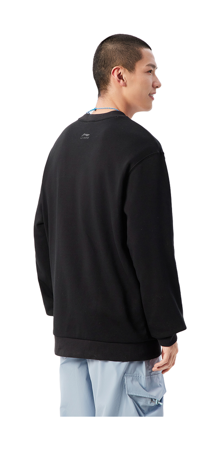 Black crewneck sweatshirt worn by model, back view; long sleeves, ribbed cuffs and hem.