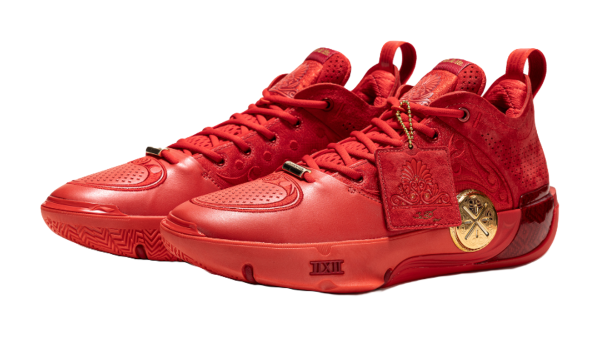 Red mid-top basketball shoes with lace-up front and gold emblem on the side.