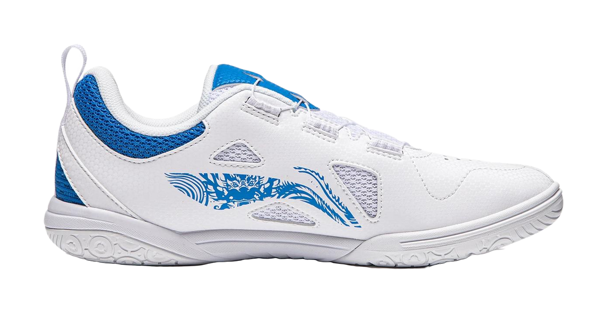 White table tennis shoe with blue heel panel, side graphic, and textured rubber outsole.