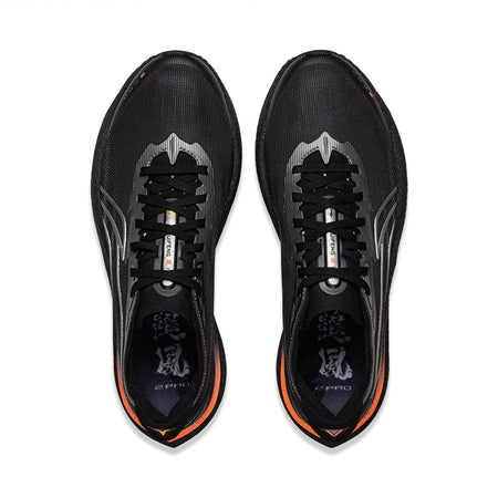 Pair of black running shoes, top view with laces, silver stripes, orange-lined collar