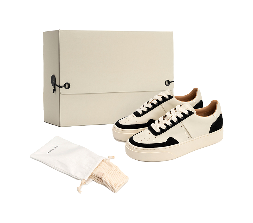 Low-top skate shoes, off-white and black lace-up style, shown with dust bag and cloth.