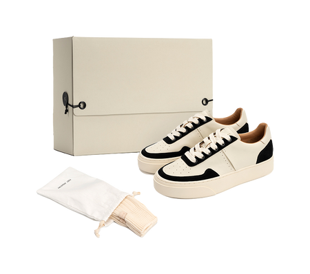 Low-top skate shoes, off-white and black lace-up style, shown with dust bag and cloth.