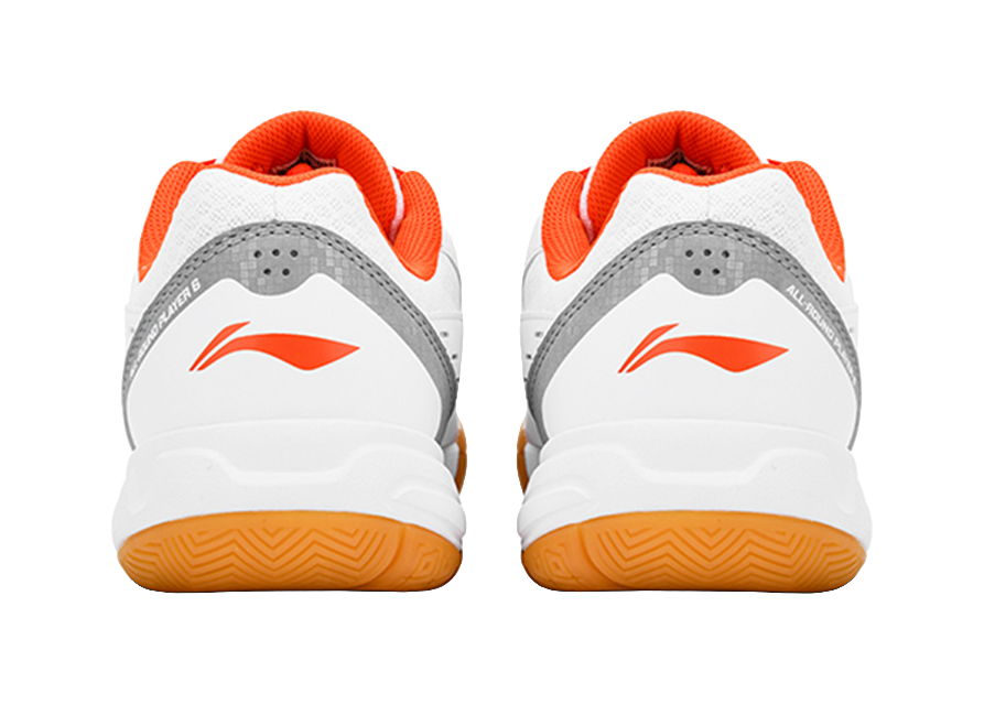Pair of white-and-orange badminton shoes with gray heel panels and orange trim
