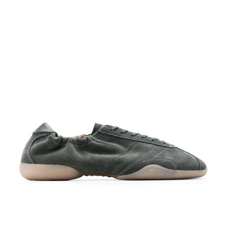 A single dark olive green leather sneaker with a beige sole, shown in profile against a white background, captured within a mobile phone screenshot interface.