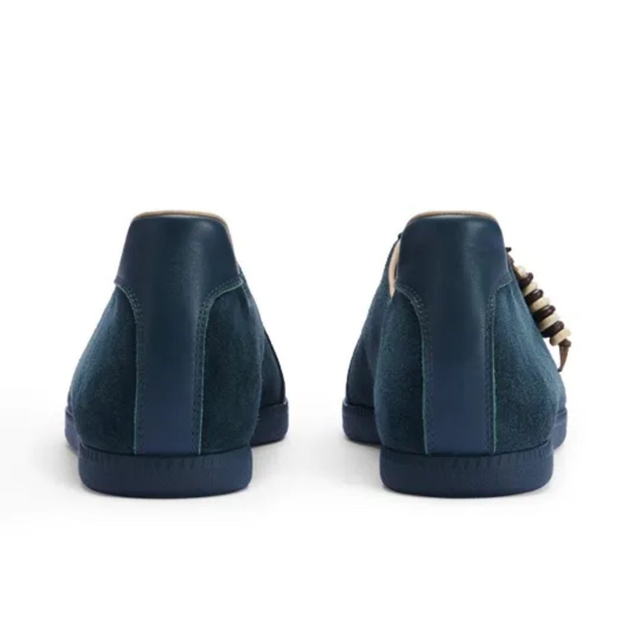 A pair of dark navy blue suede low-top sneakers shown from the back, featuring a chunky block heel and a gold chain detail along the side, displayed on a white background.