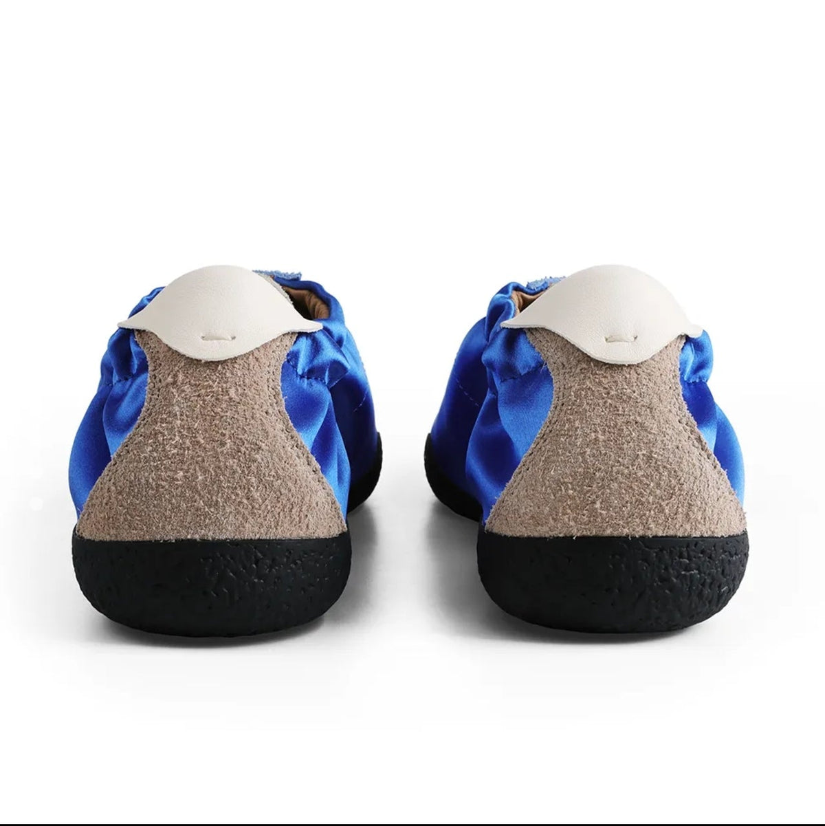 A pair of children's slip-on shoes shown from the back, featuring a blue and beige patterned upper, a beige textured midsole, and a black outsole, displayed on a white background.