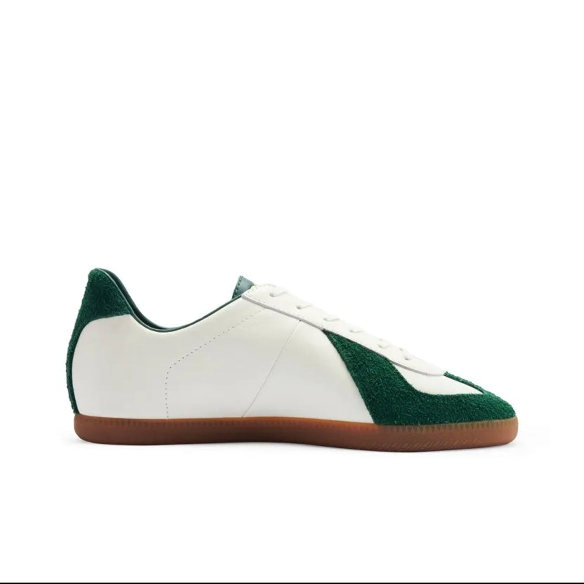 A low-top sneaker shown in side profile on a white background, with a white leather upper, dark green suede toe and heel panels, white laces, and a brown gum sole. The image appears to be a screenshot from a shopping app, with black bars and interface text around the product.