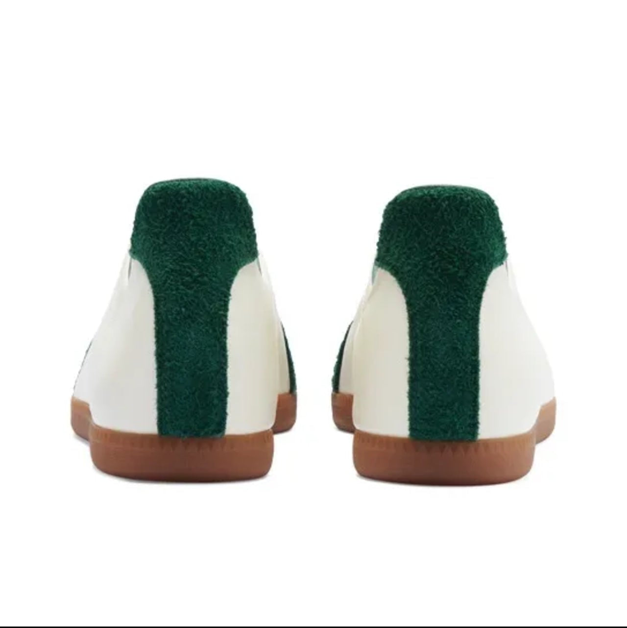 A pair of slip-on shoes shown from the back, featuring a white leather upper, a dark green plush collar, and a brown sole, set against a plain white background.