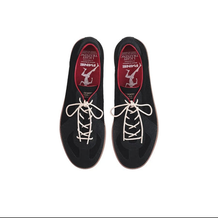 A pair of black low-top racing shoes shown from a top-down view on a white background, with white laces and red interior lining featuring a white stylized 'Z' logo. The image is captured from a mobile app screenshot with black bars and product info text below.