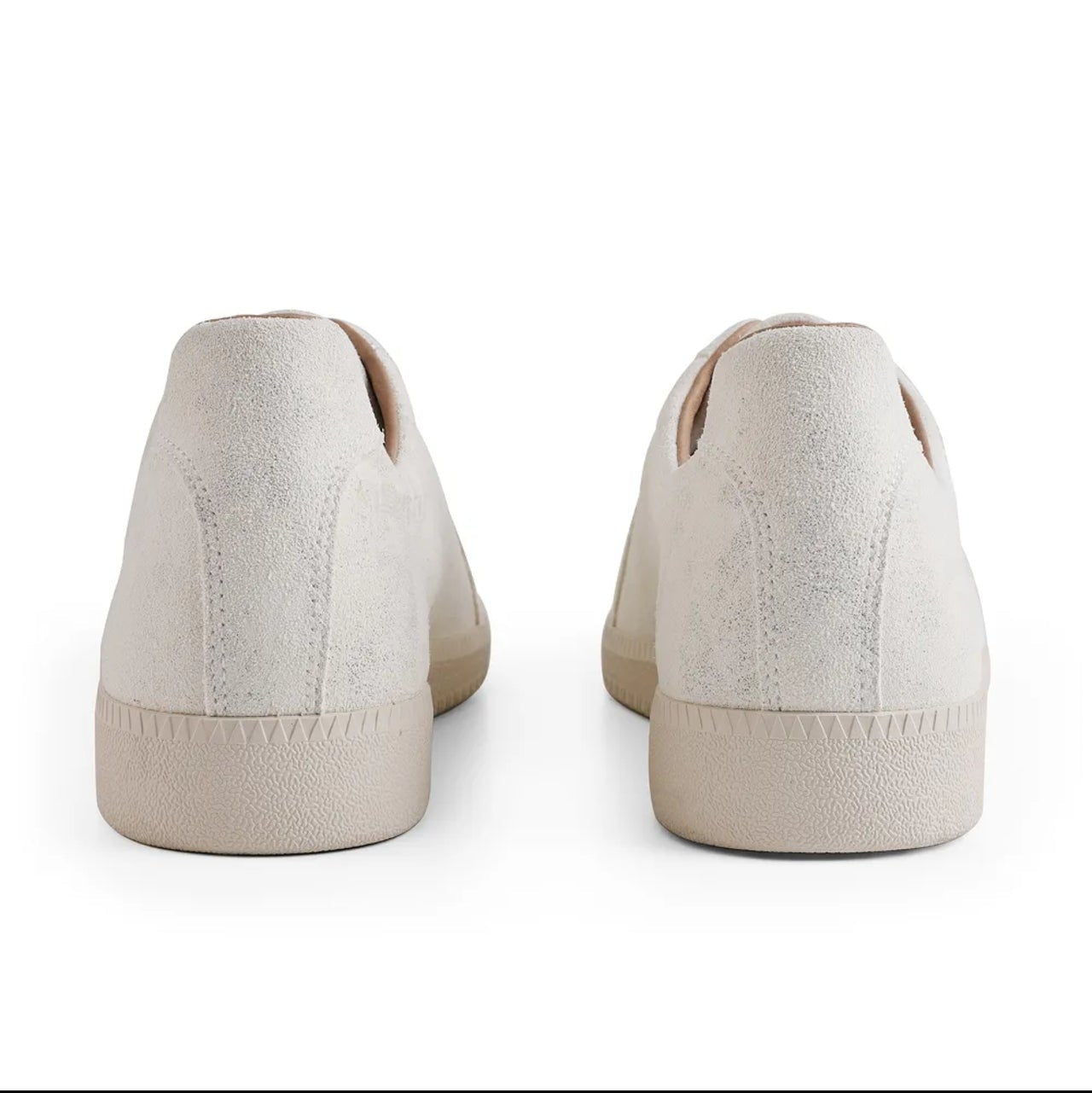 A pair of low-top slip-on sneakers shown from the back, in a warm off-white or cream color, displayed on a white background within a mobile app screenshot.