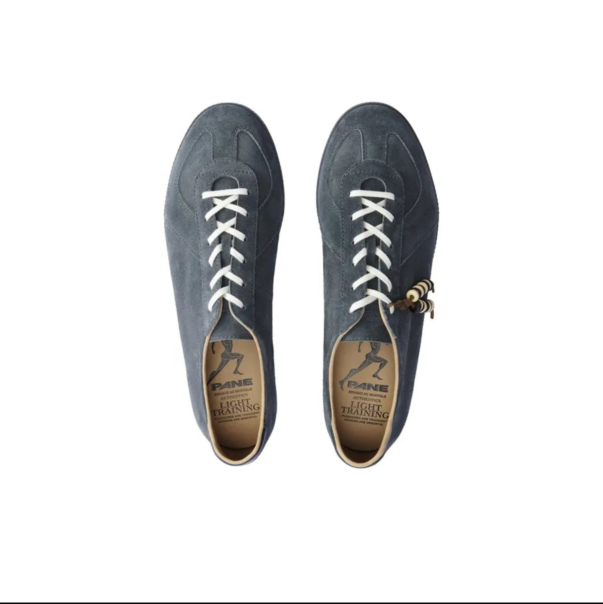 A pair of dark slate blue suede low-top sneakers with white laces and a small gold charm, shown from a top-down view on a white background.