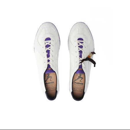 A pair of white low-top sneakers shown from above on a white background, with purple laces and a small black-and-white patterned detail near the lace area. The insoles are tan and branded, but the brand text is not clearly legible.