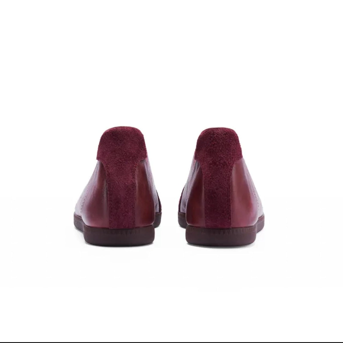 A pair of women's slip-on mule shoes shown from the back, featuring a deep burgundy-red glossy leather upper and a soft burgundy suede-like footbed. The shoes are displayed against a plain white background, framed within a mobile app screenshot with black bars and text labels.