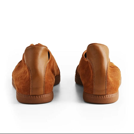 A pair of tan leather slip-on shoes shown from the back on a clean white background.