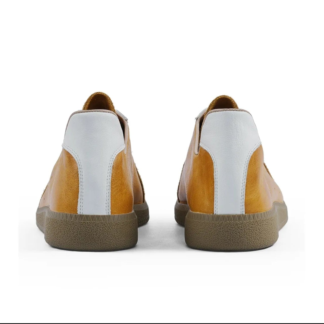 A pair of low-top sneakers shown from the back, featuring a white leather heel counter, tan leather side panels, and a brown gum sole, displayed on a white background within a mobile app interface.