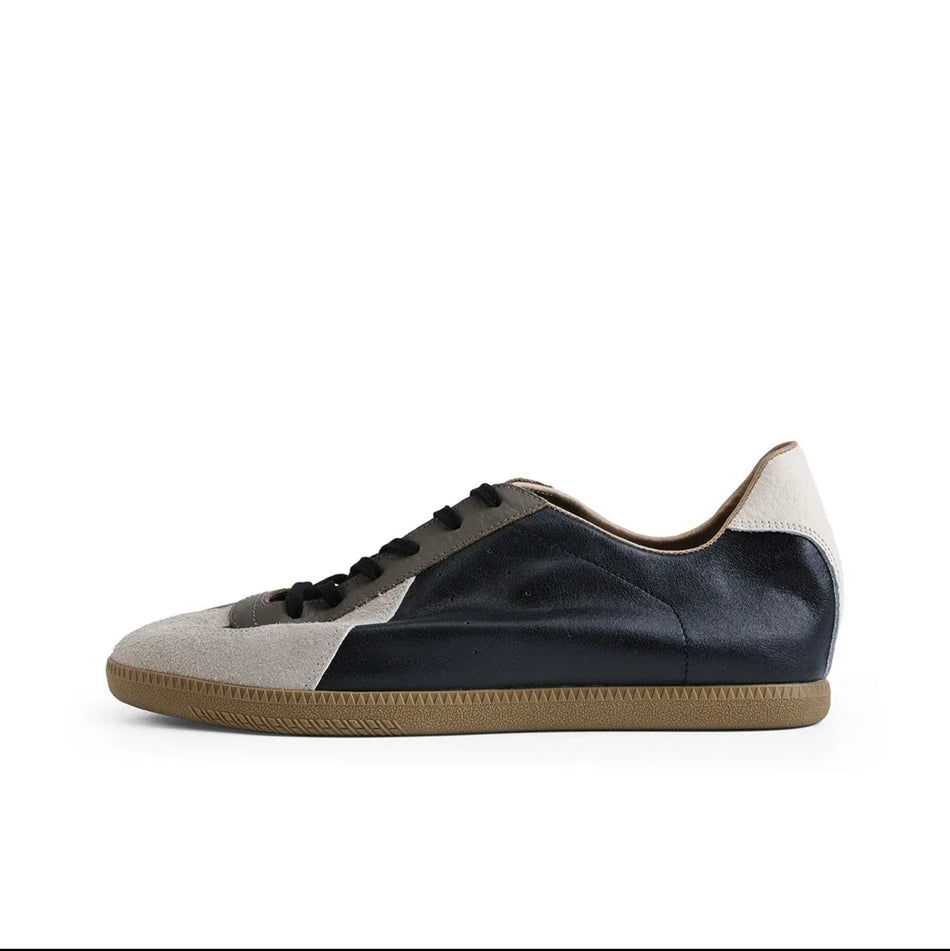A low-top sneaker shown in side profile on a white background, with a black upper, light beige side panels, black laces, and a tan gum sole. The image appears to be a screenshot from a shopping app, with black bars and interface text around the product photo.