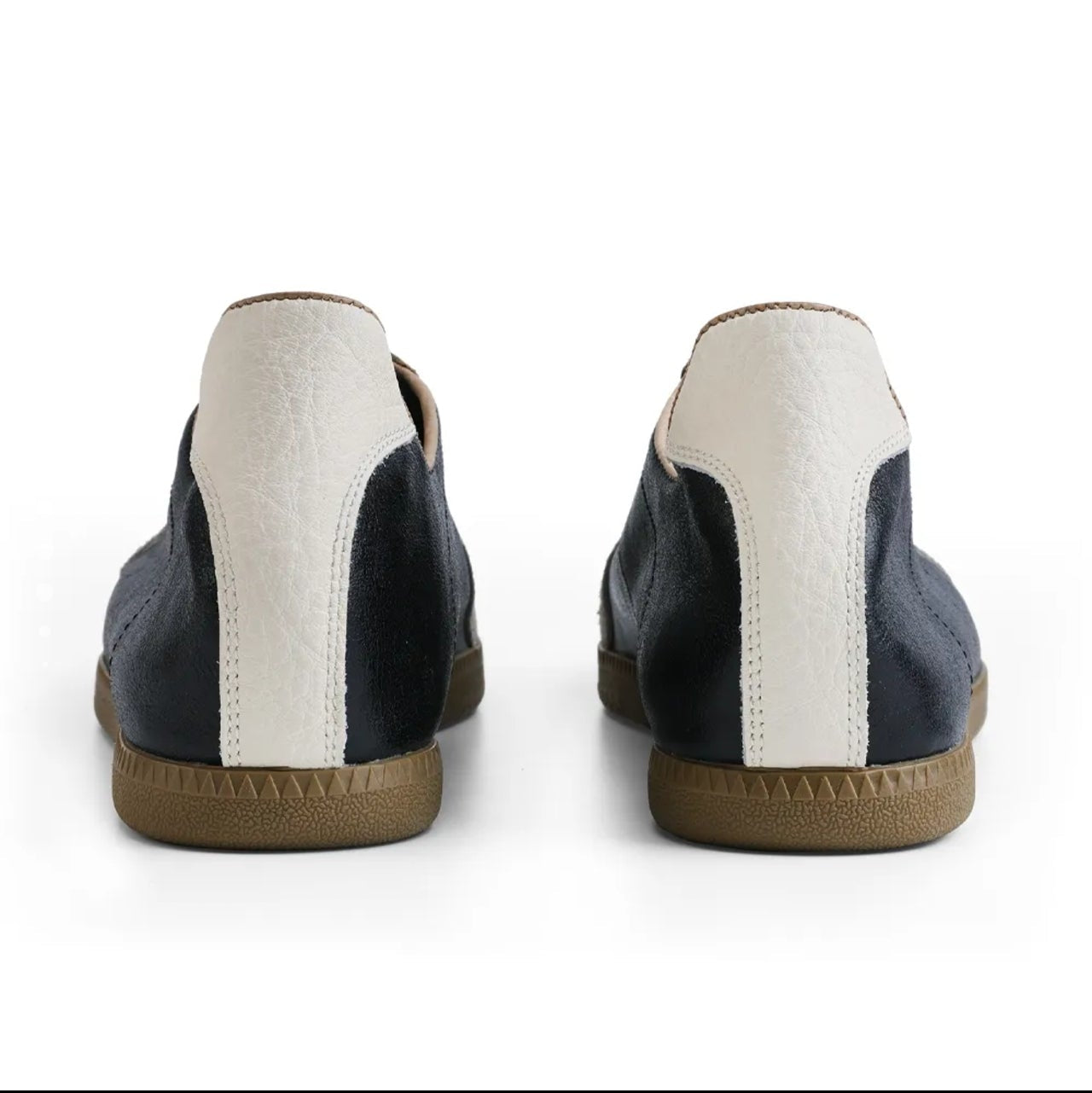 A pair of low-top casual shoes shown from the back, featuring navy blue leather panels, a vertical off-white stripe, and a tan rubber sole. The image is presented on a white background within a mobile app screenshot interface.