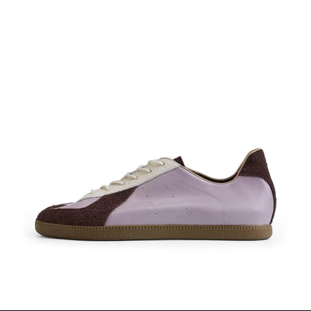 A low-top sneaker shown in side profile on a white background, with a light purple/lavender upper, dark brown heel and toe panels, white laces, and a gum brown sole. The image appears to be a screenshot from a shopping app, with black bars and text labels around the product.