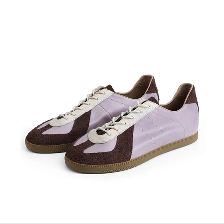 A pair of low-top sneakers shown on a white background within a mobile app screenshot. The shoes have a light lavender-purple upper with dark brown side panels and laces, and a brown gum sole.
