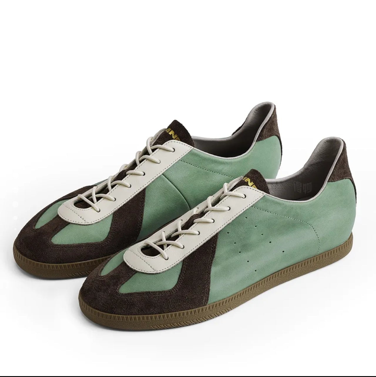 A pair of low-top sneakers with a color-blocked design featuring mint green suede, dark brown suede, and off-white leather panels, shown on a white background within a mobile app screenshot.