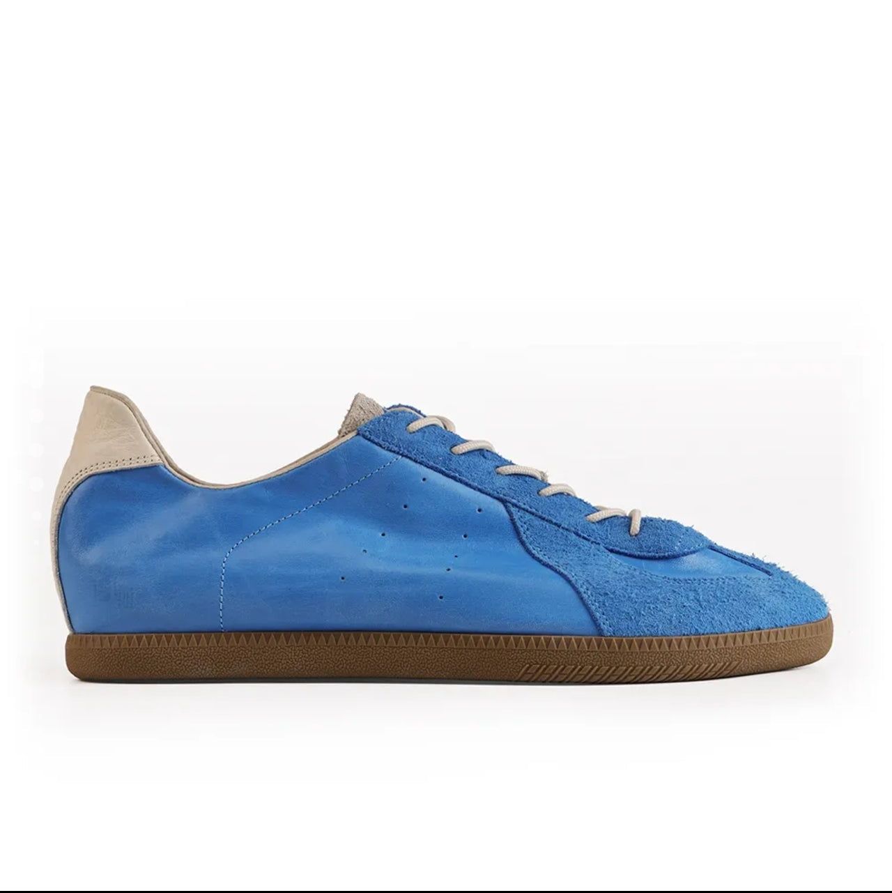 A blue suede and leather low-top sneaker with a brown gum sole, shown in a mobile app screenshot on a white background.