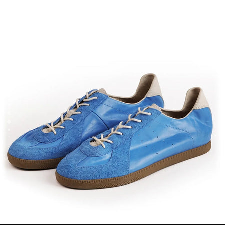 A pair of blue suede and leather sneakers with white laces and brown soles, shown on a white background within a mobile app screenshot.