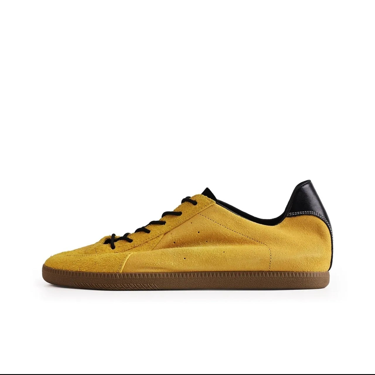 A yellow suede sneaker with black laces, a black heel tab, and a brown gum sole, shown against a white background. The image is a screenshot from a shopping app with black bars at the top and bottom and Chinese interface icons.