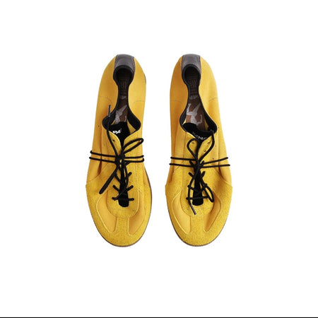 A pair of yellow suede shoes with black laces and black heel caps, shown from a top-down view on a white background.